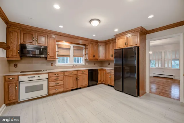 a kitchen with stainless steel appliances granite countertop a refrigerator oven a sink dishwasher and a stove with wooden floor