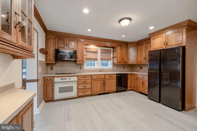 a kitchen with stainless steel appliances granite countertop a refrigerator a sink dishwasher a stove oven and a dining table with wooden floor