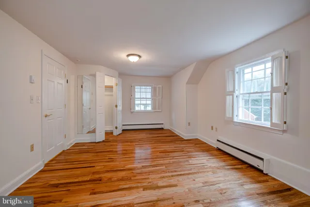 a view of an empty room with window and wooden floor