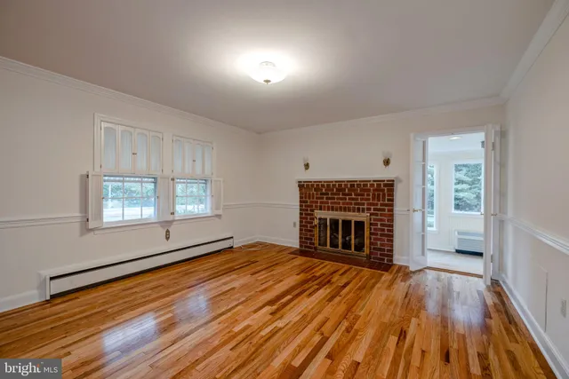 an empty room with windows fireplace and wooden floor