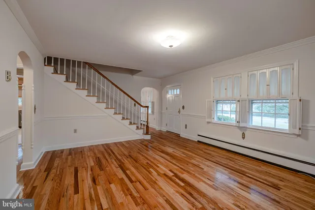 a view of an empty room with wooden floor and fan