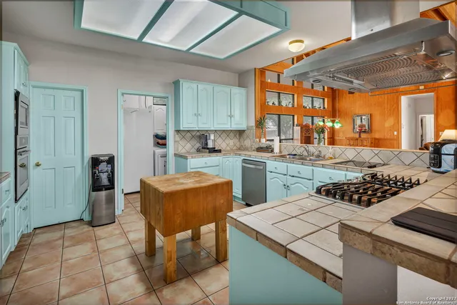 a kitchen with furniture a large window and stainless steel appliances