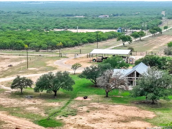 an aerial view of a houses with outdoor space and trees all around