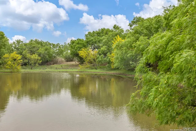 an aerial view of a houses with outdoor space and trees all around