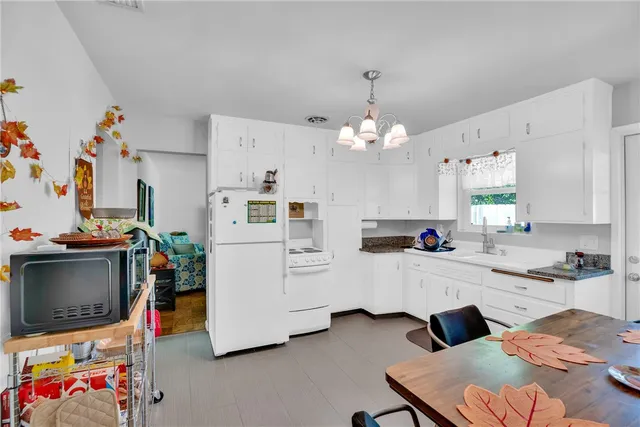 a dining room with wooden floor a chandelier a wooden table and chairs