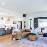 a living room with furniture couches and a dining table with wooden floor