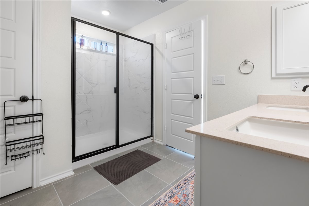 18501 Spotted Eagle Lane Elgin, TX 78621 - Photo 29 of 40 A well-lit primary bathroom featuring a spacious walk-in shower and elegant double vanity.