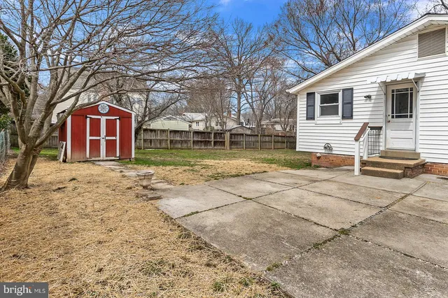 a backyard of a house with large trees and barbeque oven