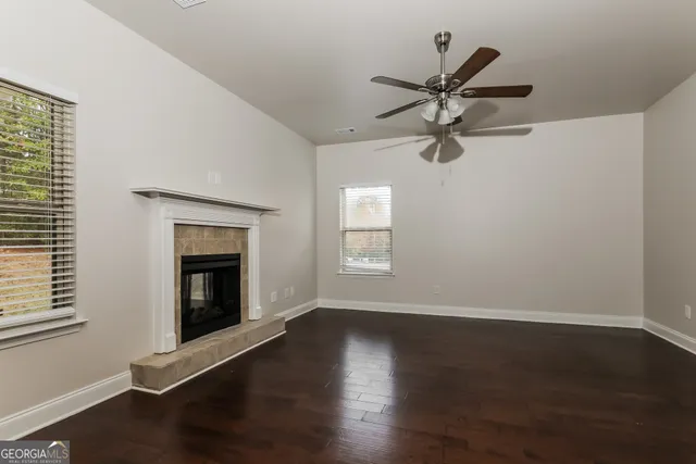 a view of a livingroom with a fireplace a ceiling fan and wooden floor