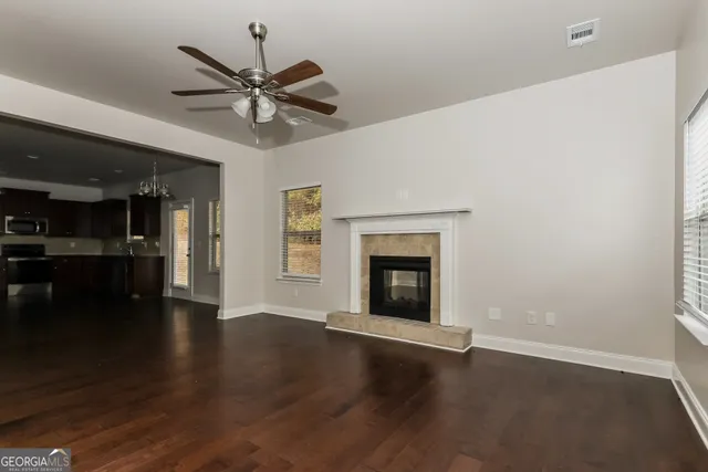 a view of an empty room with wooden floor and a fireplace