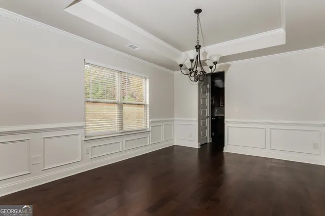 an empty room with wooden floor chandelier and windows