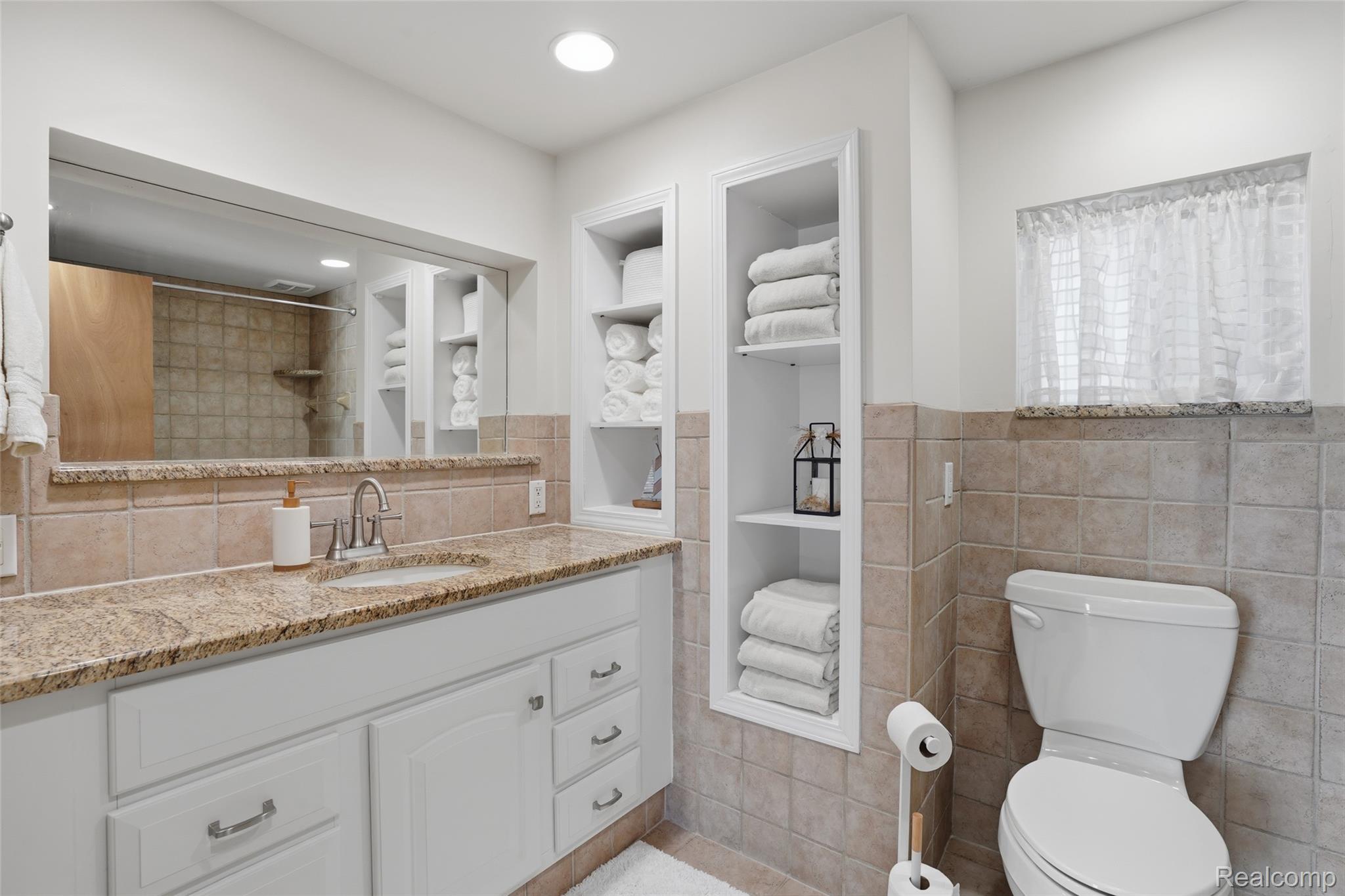 7217 Andersonville Road Clarkston, MI 48346 - Photo 16 of 65 Main Floor Bathroom featuring a white vanity with a granite countertop, undermount sink, and brushed nickel faucet