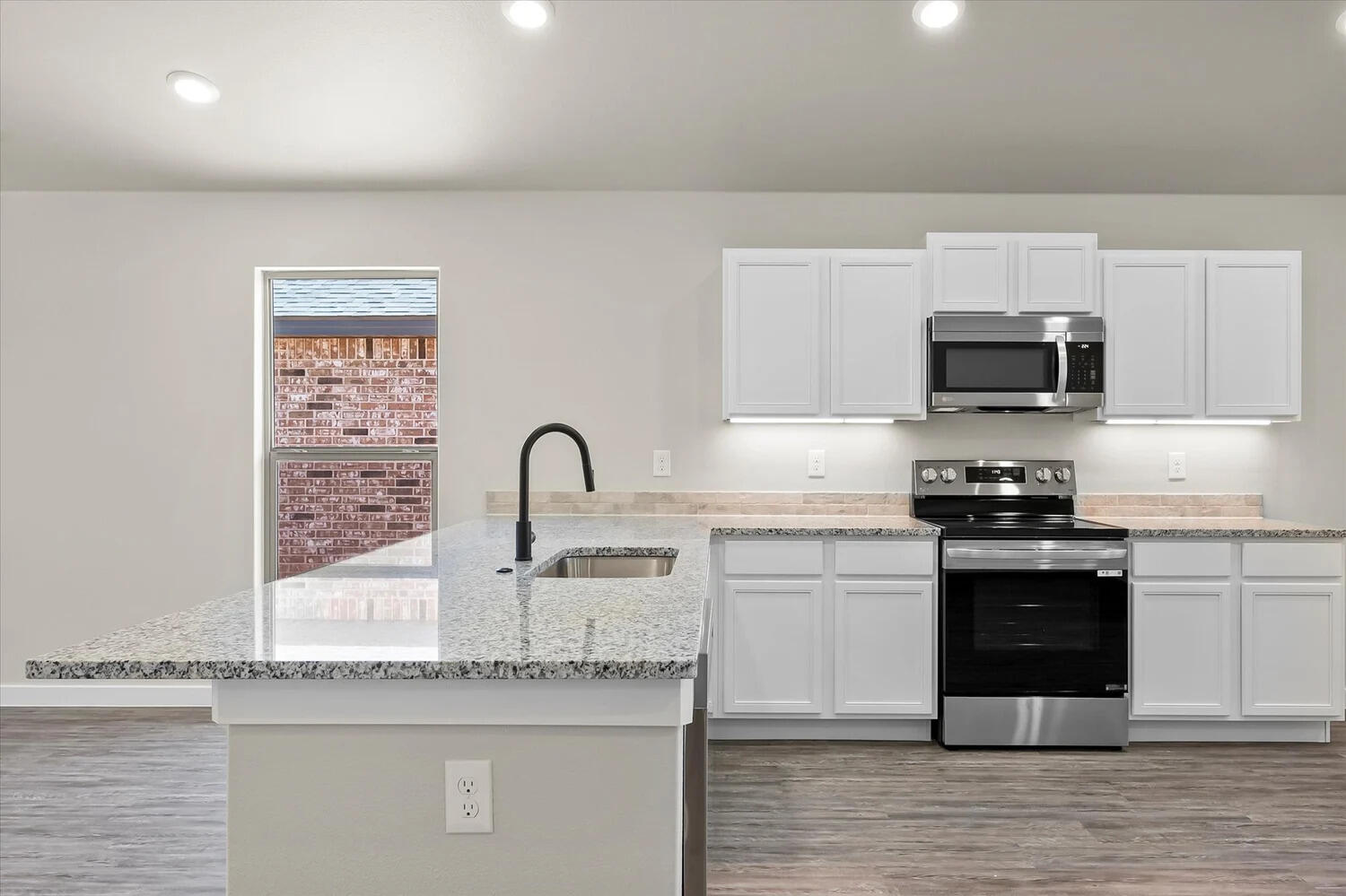 7446 29th Street Lubbock, TX 79407 - Photo 4 of 11 a kitchen with granite countertop a stove and a sink