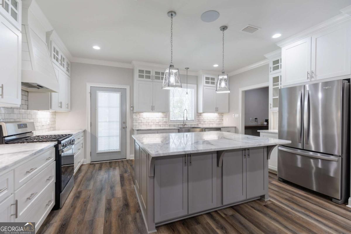 601 Pine Point Circle Valdosta, GA 31602 - Photo 11 of 45 a kitchen with stainless steel appliances granite countertop a refrigerator a sink dishwasher a stove and white cabinets with wooden floor