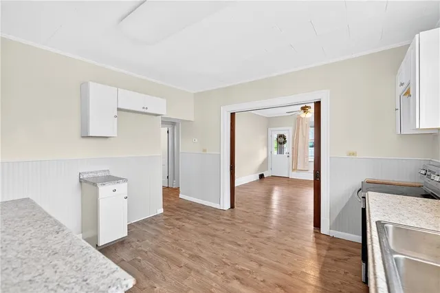 a view of a hallway to a bedroom with wooden floor and cabinet