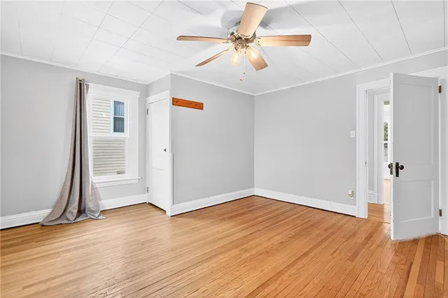 an empty room with wooden floor and ceiling fan