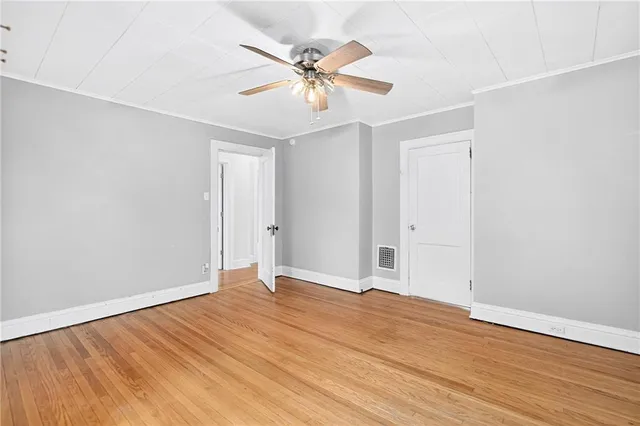 an empty room with wooden floor and ceiling fan