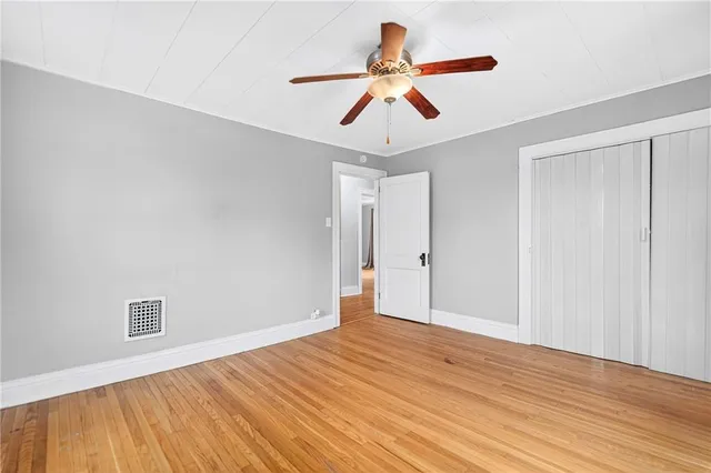 an empty room with wooden floor and ceiling fan