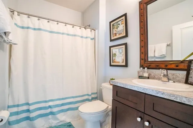 a bathroom with a granite countertop sink toilet and a mirror