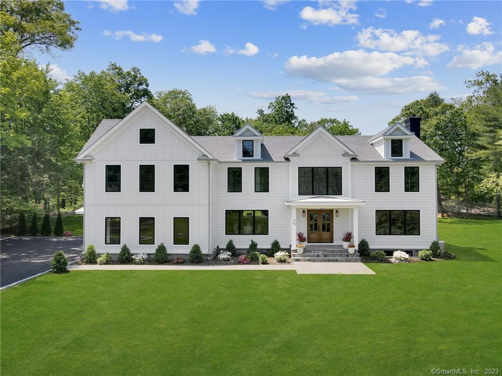 a large white building with a swimming pool and lawn chairs with plants