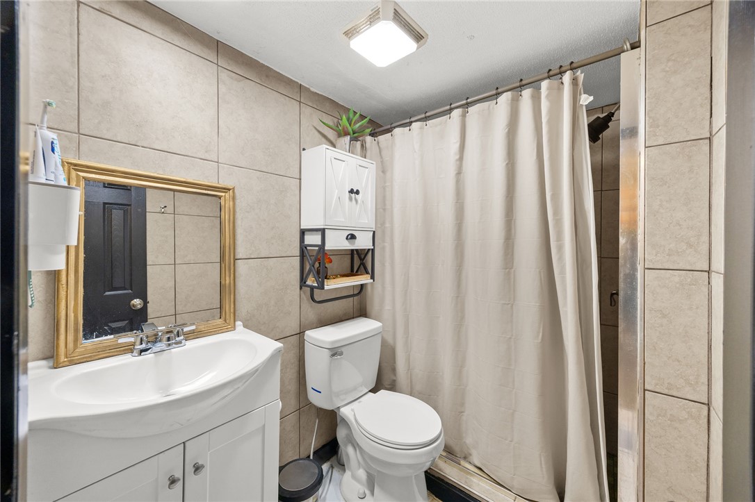 217 Old River Road Pelzer, SC 29669 - Photo 17 of 30 A well-appointed bathroom with full-height tiled walls and convenient wall-mounted storage offers practical comfort.