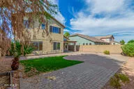 a view of a white house next to a yard with big trees