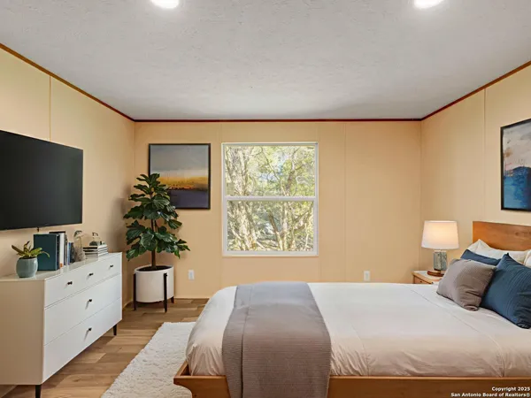 a bedroom with a large bed and a flat tv screen on dresser