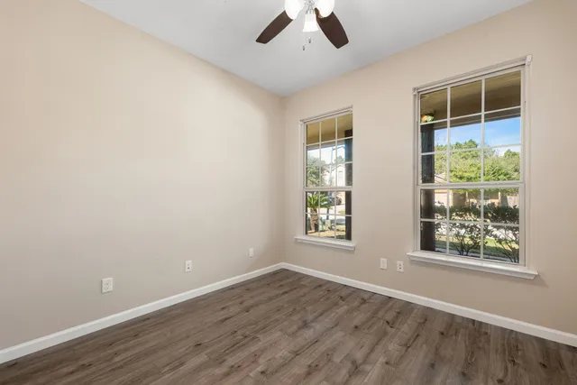 an empty room with windows and ceiling fan