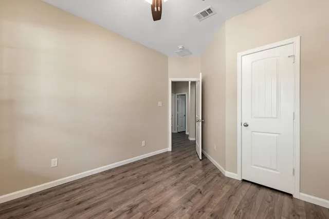 a view of an empty room and wooden floor ceiling fan