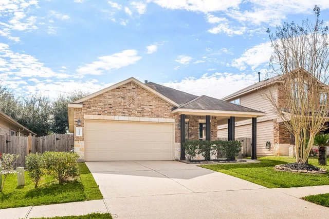 a view of a white house next to a yard and a large tree