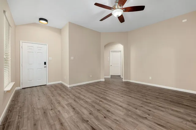 an empty room with wooden floor and windows