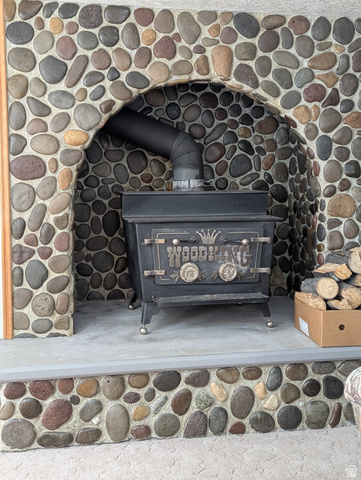 1040 West Mill Road Ferron, UT 84523 - Photo 66 of 117 River rock fireplace surround with an arched opening, featuring a solid fuel burning stove