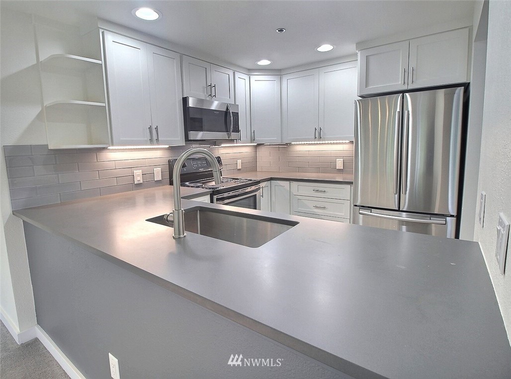 19404 Bothell Way Northeast, Unit B304 Bothell, WA 98011 - Photo 13 of 38 a kitchen with stainless steel appliances a refrigerator a sink a stove a microwave and island