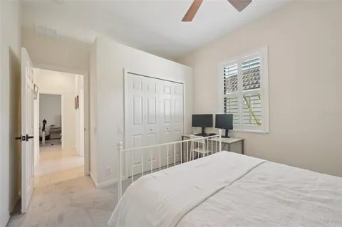 a bedroom with a bed and a computer on a desk next to a window