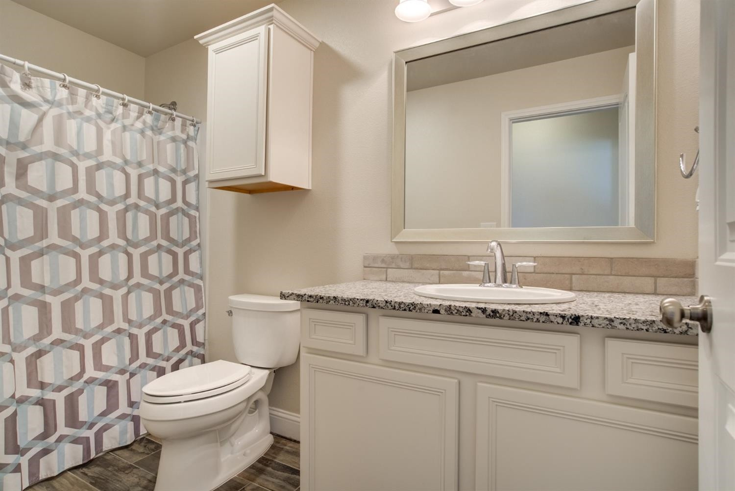 8806 Rochester Avenue Lubbock, TX 79424 - Photo 19 of 25 a bathroom with a granite countertop sink a toilet and a mirror