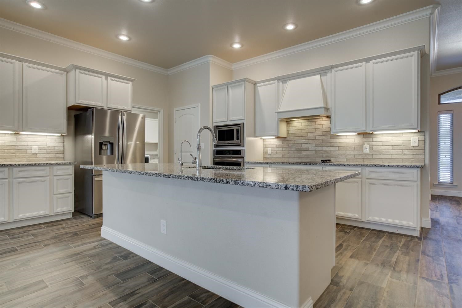 8806 Rochester Avenue Lubbock, TX 79424 - Photo 10 of 25 a kitchen with kitchen island granite countertop a sink cabinets and stainless steel appliances