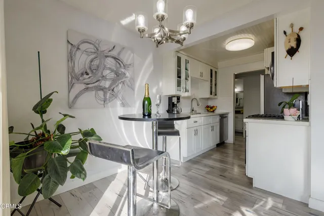 a living room with couches chandelier and kitchen view