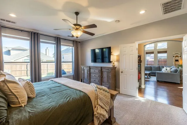 a bedroom with a large bed a flat tv screen and a chandelier