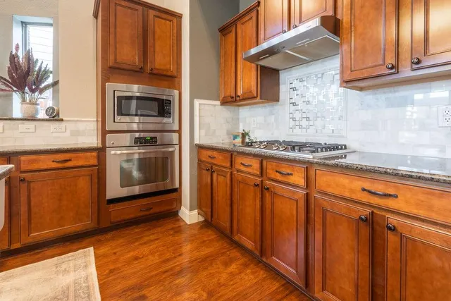 a kitchen with stainless steel appliances granite countertop a refrigerator and wooden cabinets