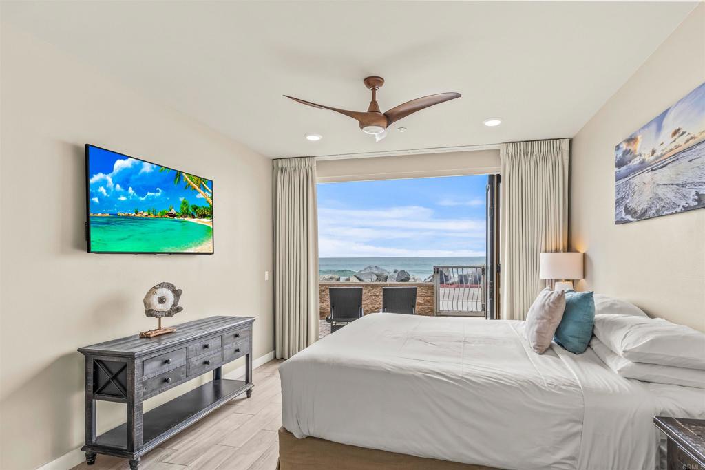 700 South The Strand, Unit 102 Oceanside, CA 92054 - Photo 14 of 25 a bedroom with a balcony a bed and a flat screen tv