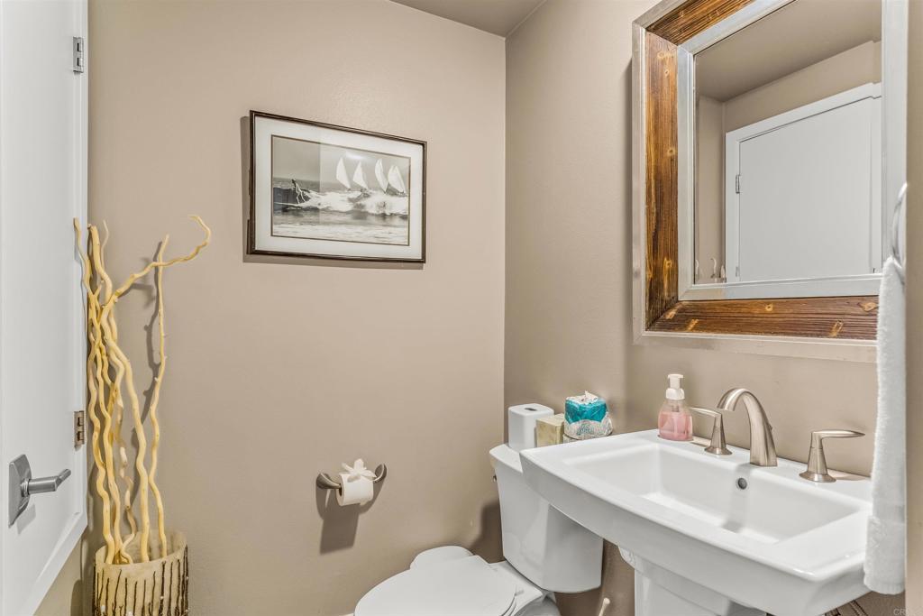 700 South The Strand, Unit 102 Oceanside, CA 92054 - Photo 22 of 25 a bathroom with a toilet a sink and a mirror