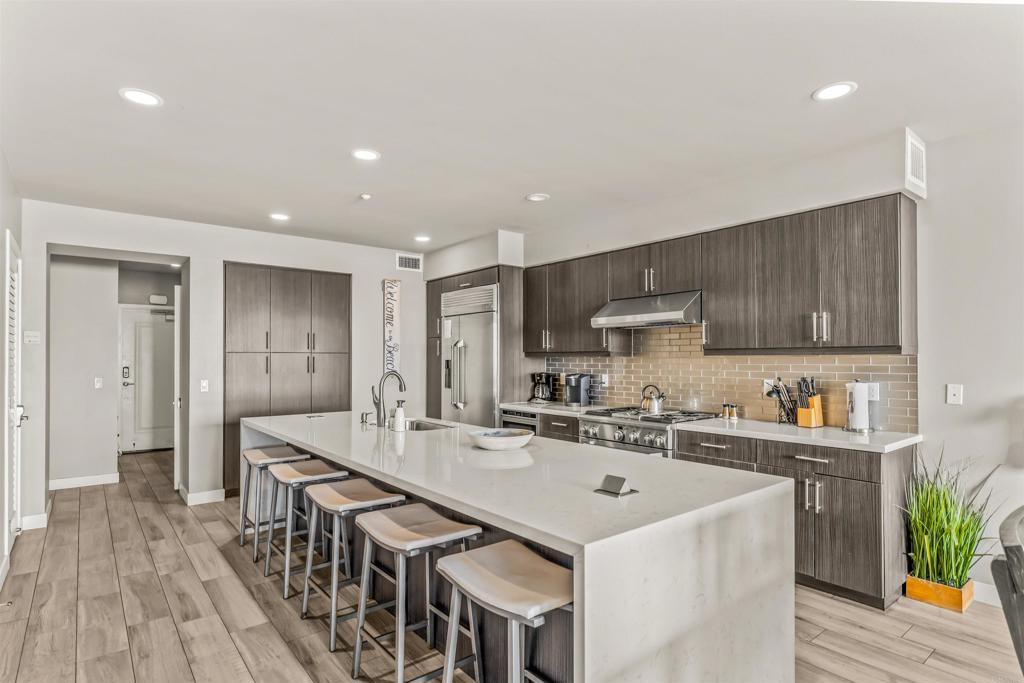 700 South The Strand, Unit 102 Oceanside, CA 92054 - Photo 6 of 25 a kitchen with stainless steel appliances a sink a stove a refrigerator cabinets and living room view