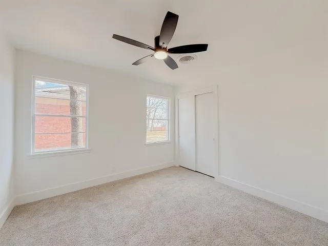 an empty room with windows and fan