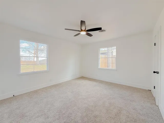 an empty room with windows and fan