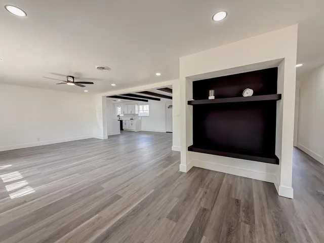 a view of an empty room with wooden floor and a fireplace