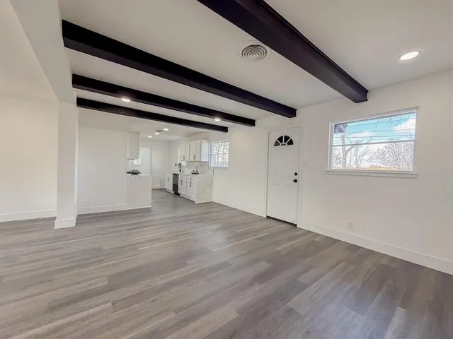 a view of empty room with wooden floor and window