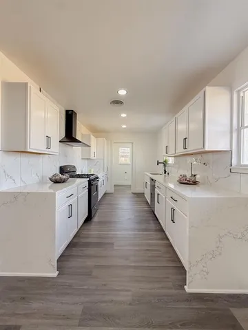 a large white kitchen with kitchen island a sink a stove a refrigerator and white cabinets
