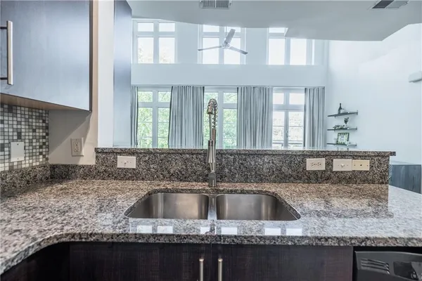 a kitchen with granite countertop a sink window and cabinets