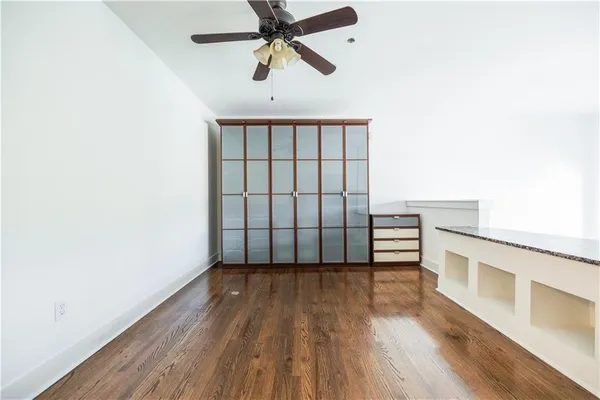 an empty room with wooden floor fan and windows