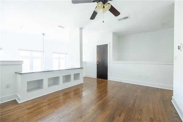 a view of an empty room with wooden floor and window
